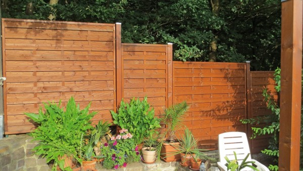 Beispiel mit Dichtzaun Klassik teak lasiert und Pfostenabdeckkappe